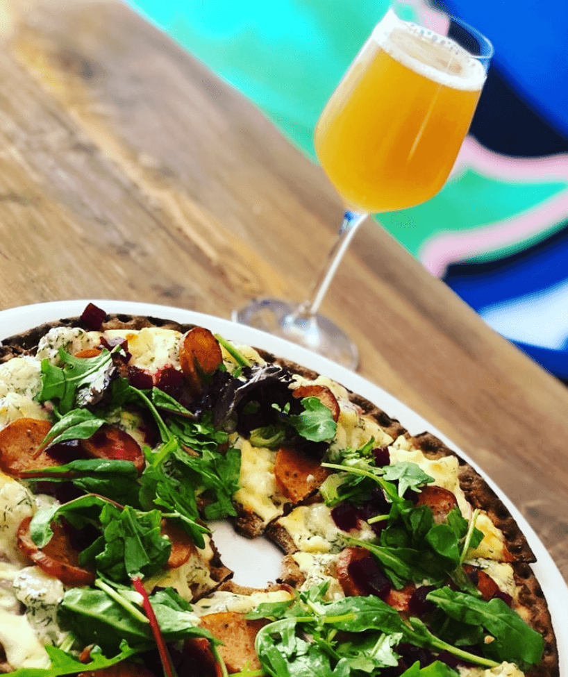 Knäckebrödspizza och ett glas öl på ett bord inne på UDDA